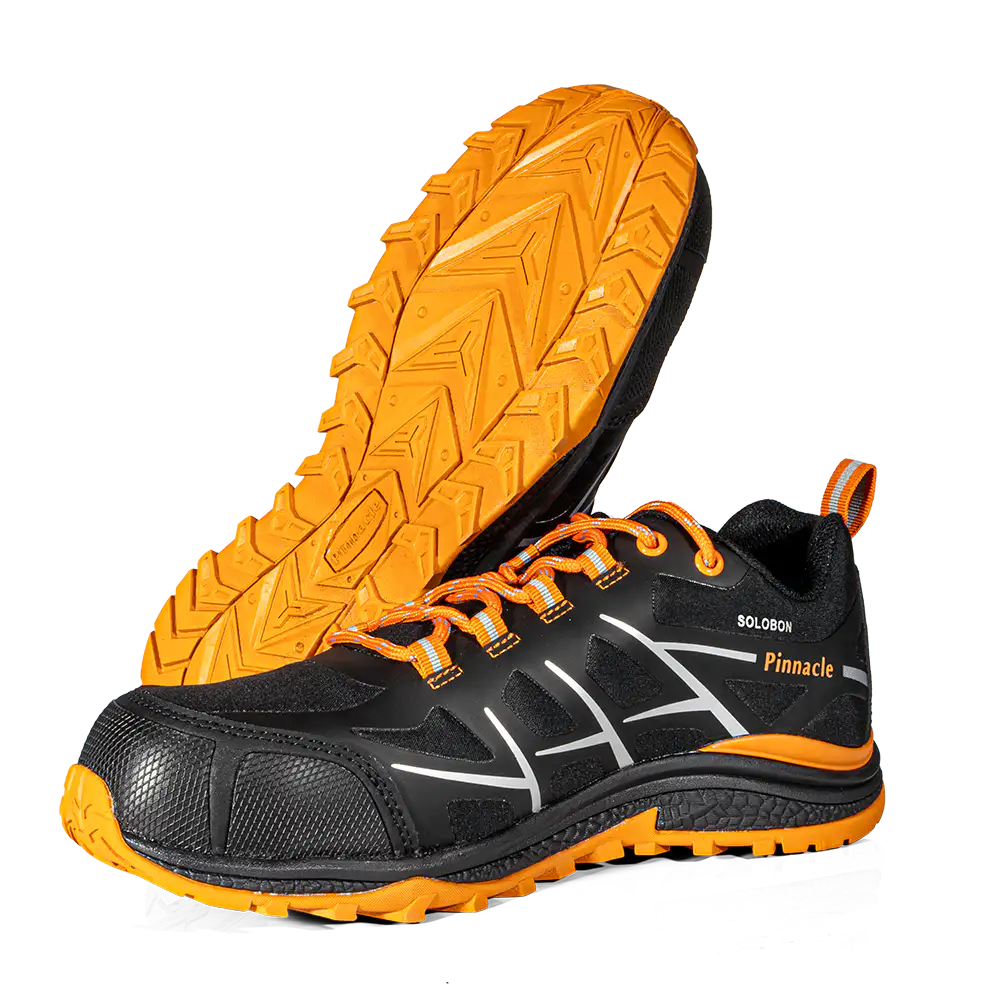 A pair of black and orange athletic shoes, with one shoe standing upright to show the side profile and the other lying on its side to display the textured orange outsole. The shoes feature white graphic accents on the side, orange laces, and the brand name 'Pinnacle' along with 'SOLOMON' printed on the side.
