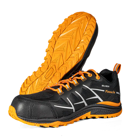A pair of black and orange athletic shoes, with one shoe standing upright to show the side profile and the other lying on its side to display the textured orange outsole. The shoes feature white graphic accents on the side, orange laces, and the brand name 'Pinnacle' along with 'SOLOMON' printed on the side.